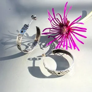 boucles d'oreilles créoles ethniques à côté d'une fleur violette