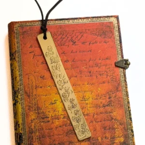 marque-page gravé de dent-de-lions posé sur un livre bleu