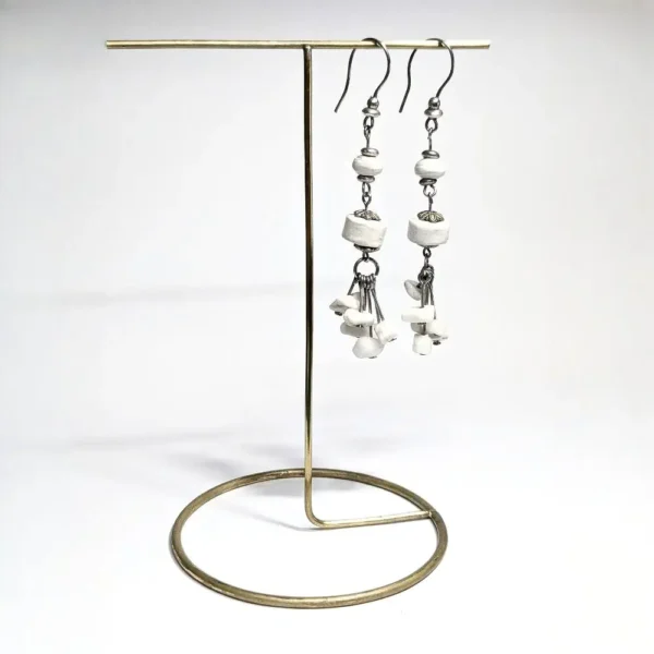 boucles d'oreilles de pierres blanches pendues à un présentoir en laiton