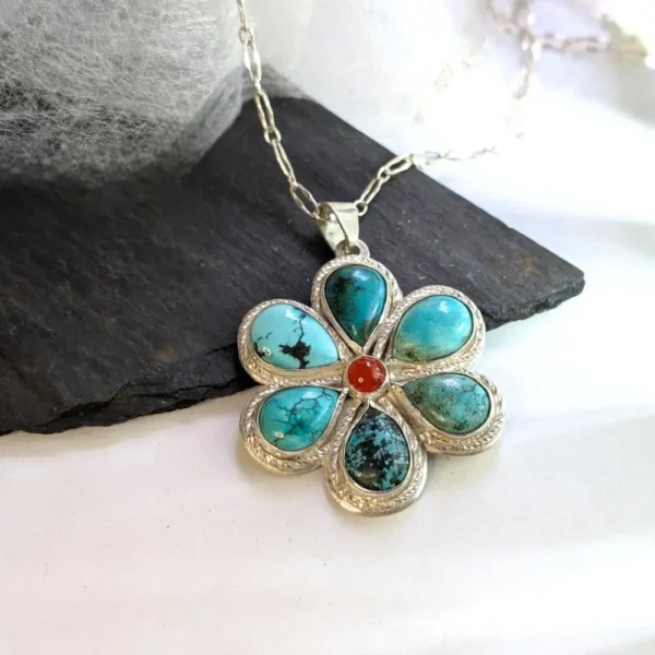 pendentif fleur turquoise posé sur une pierre