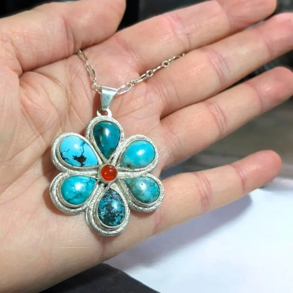 pendentif fleur turquoise posé sur une main