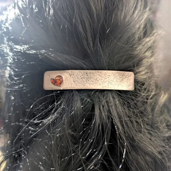barrette argentée avec un cœur couleur ambre en résine sur des cheveux