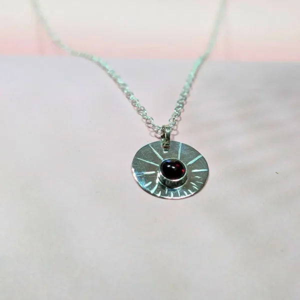 collier à la médaille ronde avec un grenat