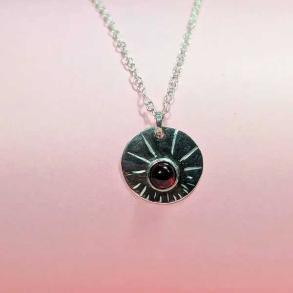 collier et médaille en arget massif avec un grenat au centre