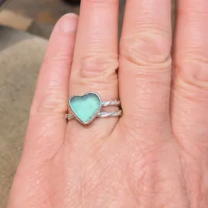bague coeur en verre de mer sur une main de femme